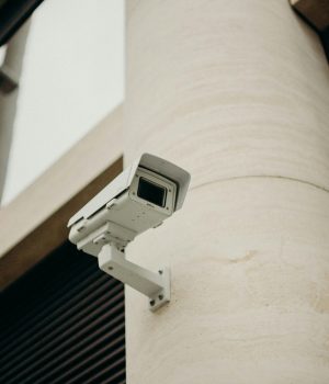 Close-up of a CCTV camera on a concrete building, symbolizing security and technology.